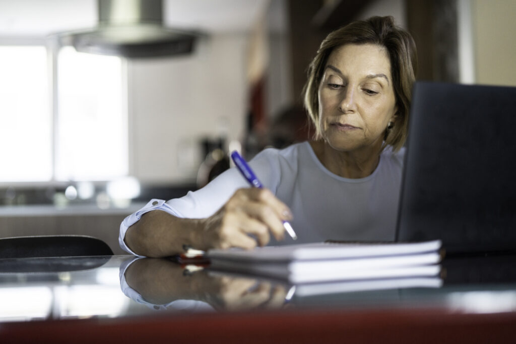 older woman taking notes laptop gettyimages