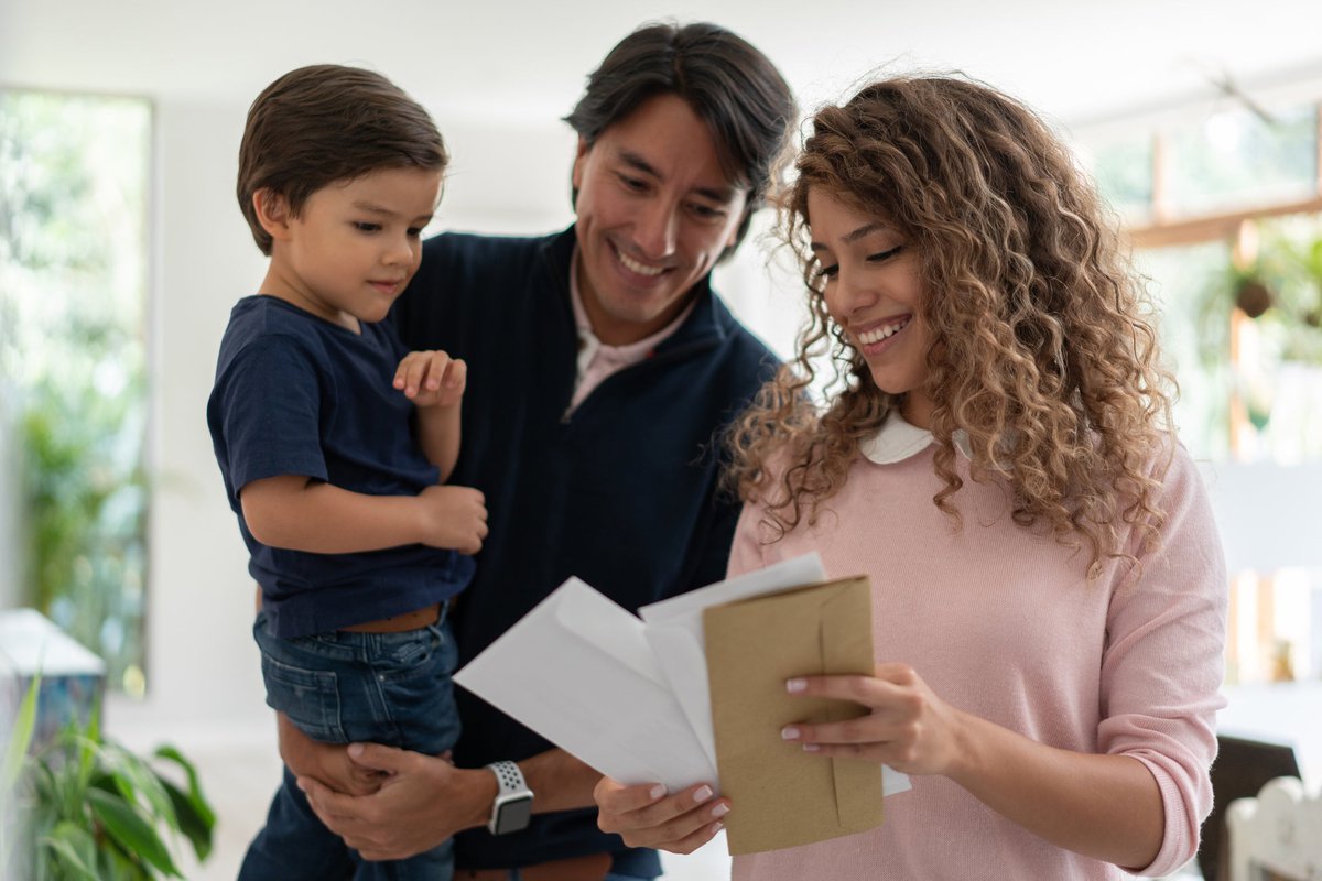 Young family smiles while looking through mai.width YCkchbc