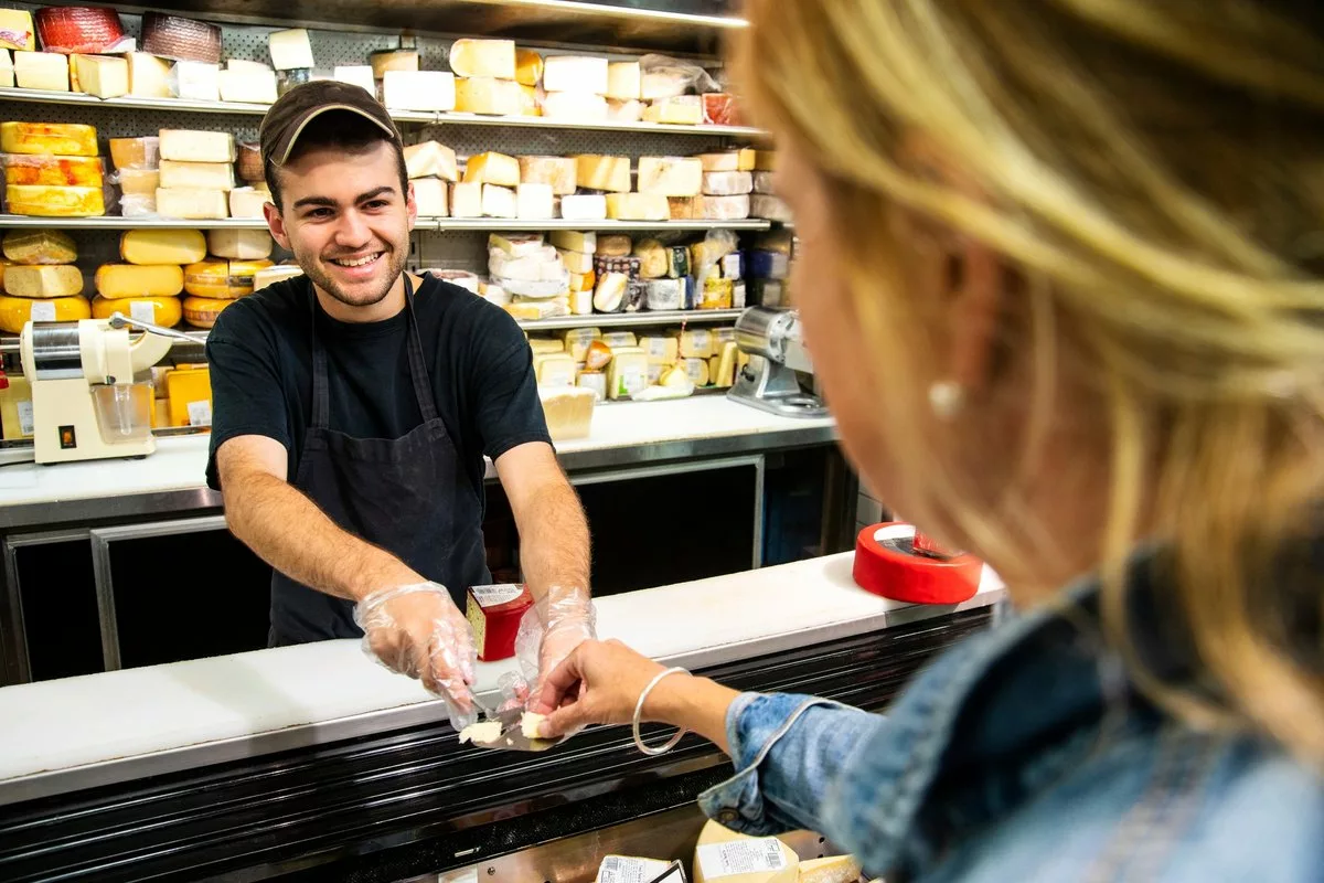 Employee handing sample of cheese to woman sh.width QAGKAOI.jpg