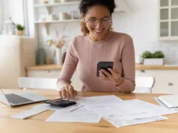 smiling person looking at smartphone and typing on calculator.jpg