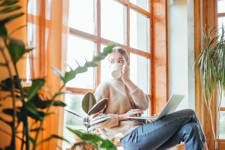 woman with coffee and laptop looking out wind.width .jpg