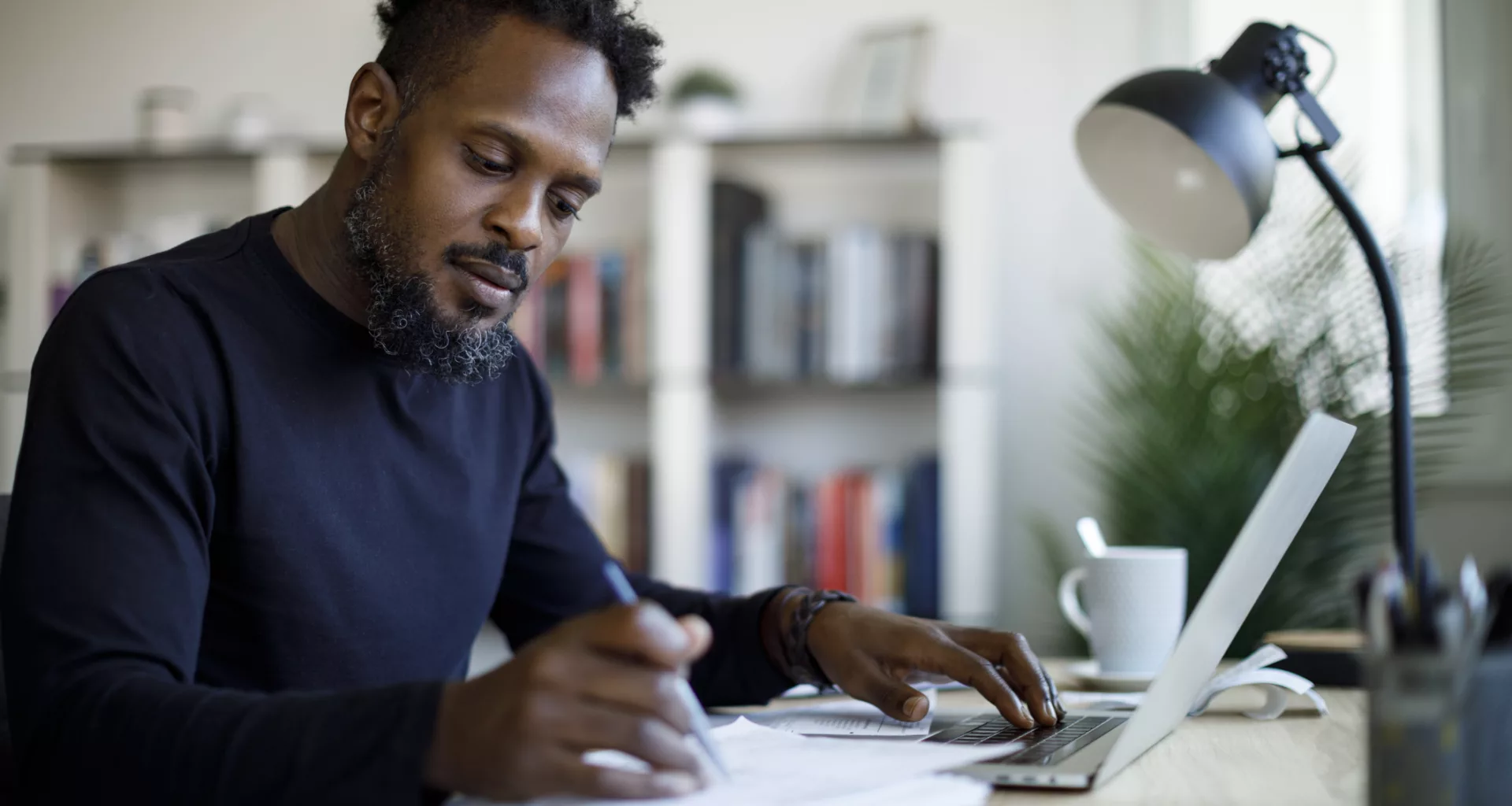 person sitting at a desk looking at a laptop and documents.jpg